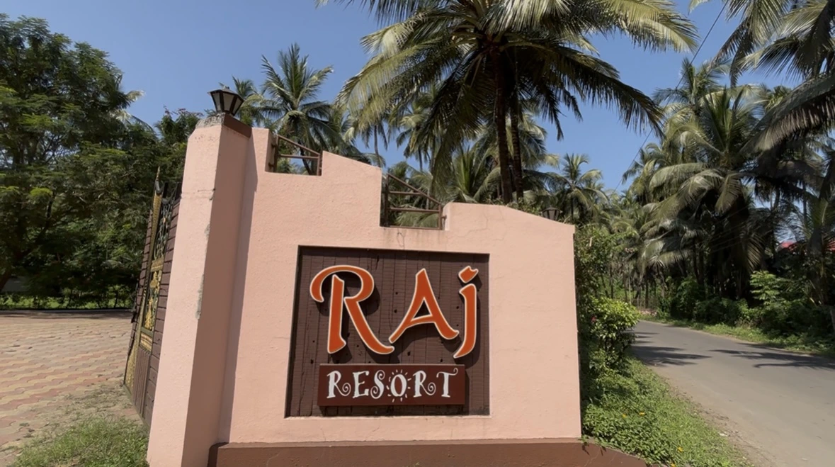 Exterior view of Raj Resort buildings surrounded by lush palm trees in Kelva